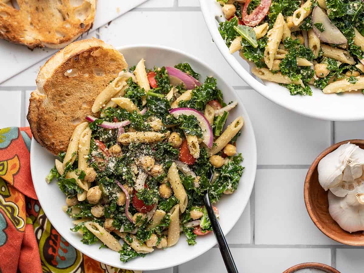 A bowl of kale pasta salad next to the serving dish.