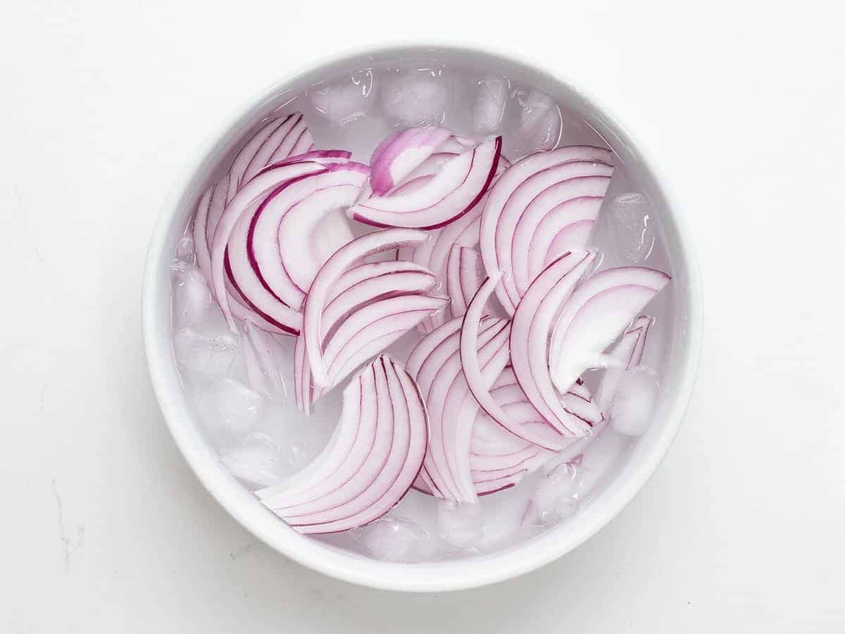 sliced red onion in a bowl of ice water.