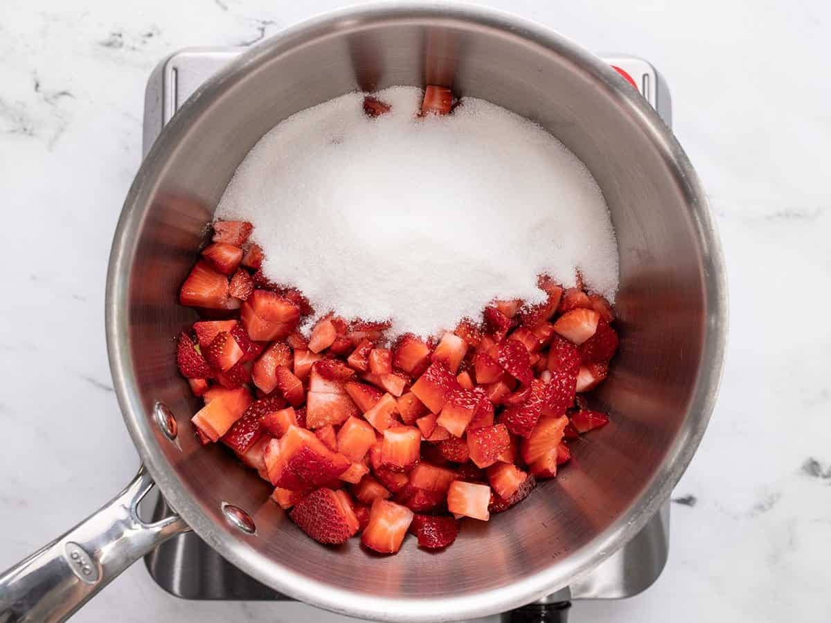 Chopped strawberries in pot with sugar.