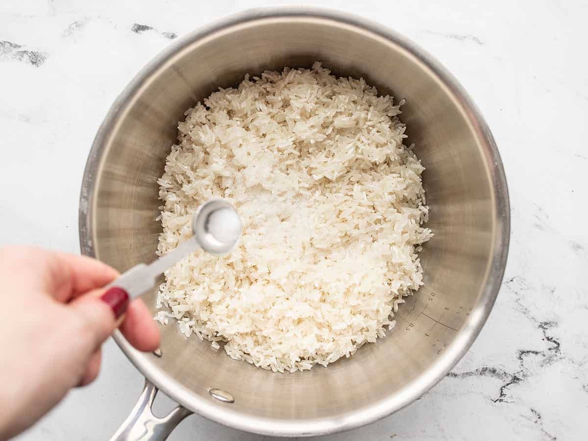 salt being added to a sauce pot with rice