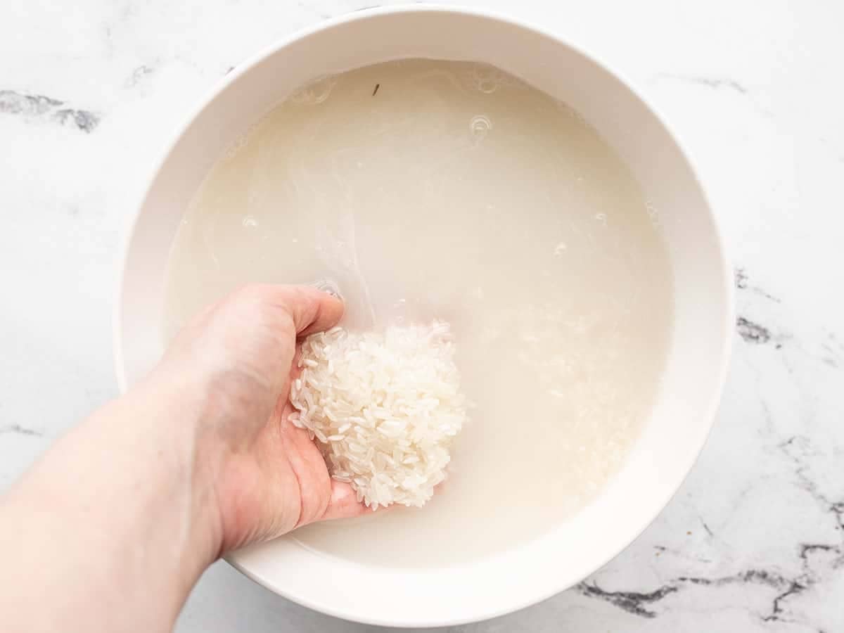 Rice being rinsed in a bowl.