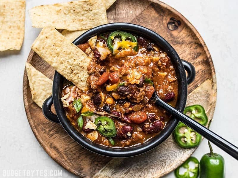 Chili in a bowl with tortilla chips being eaten
