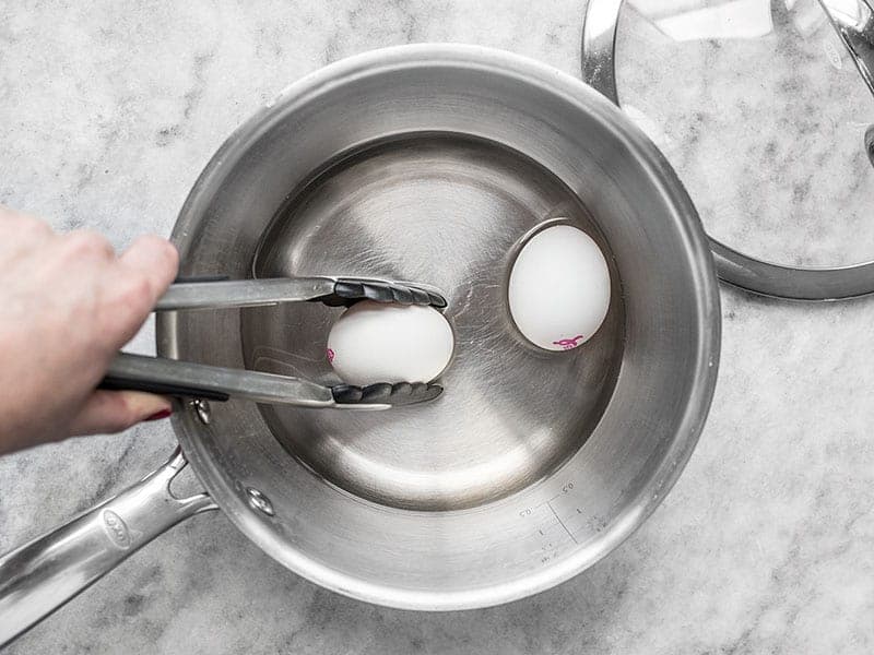 Eggs being added to a pot of boiling water 
