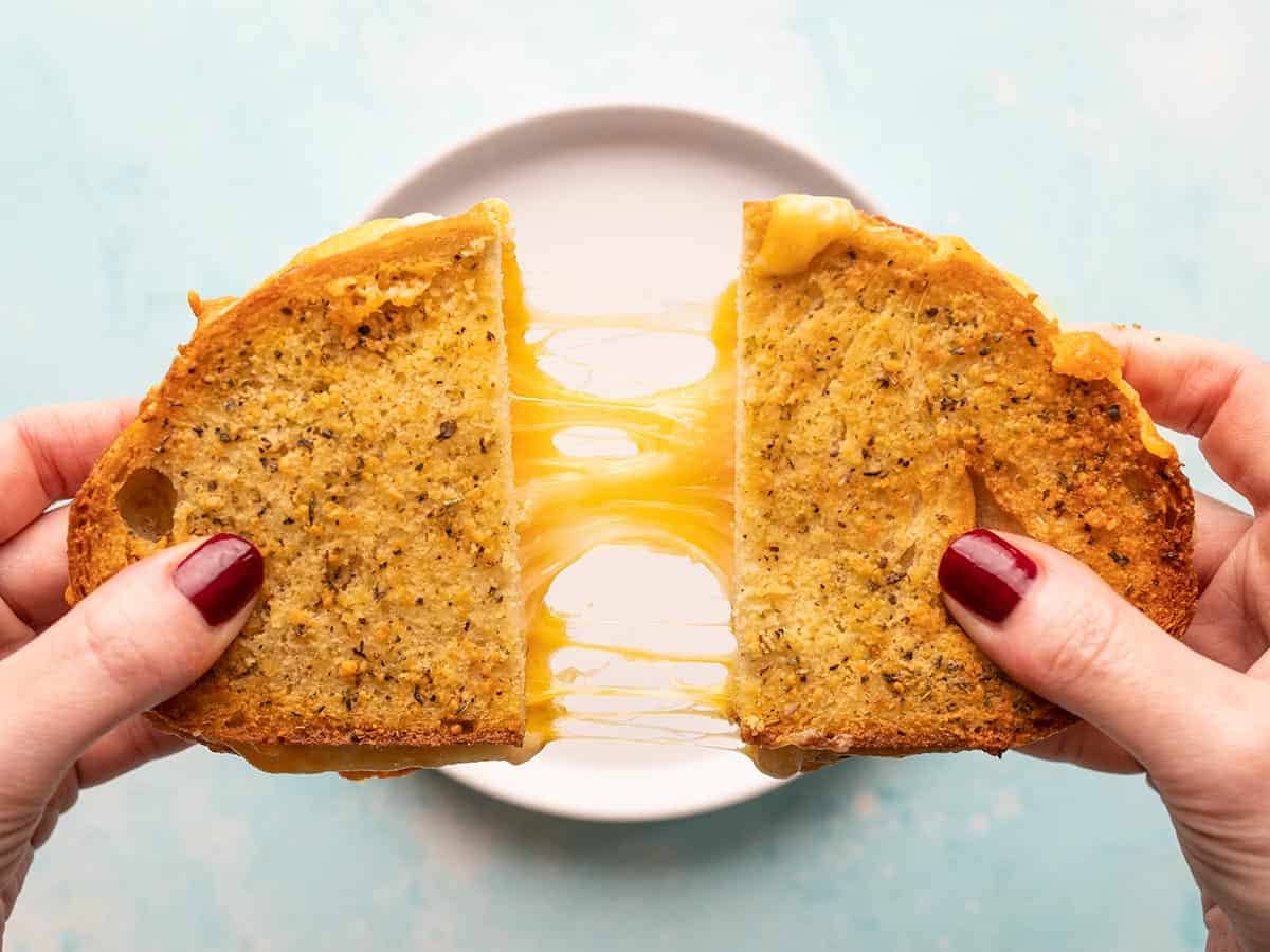 Air fryer grilled cheese being pulled apart by two hands.