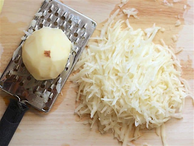 Shredding potato with cheese grater 