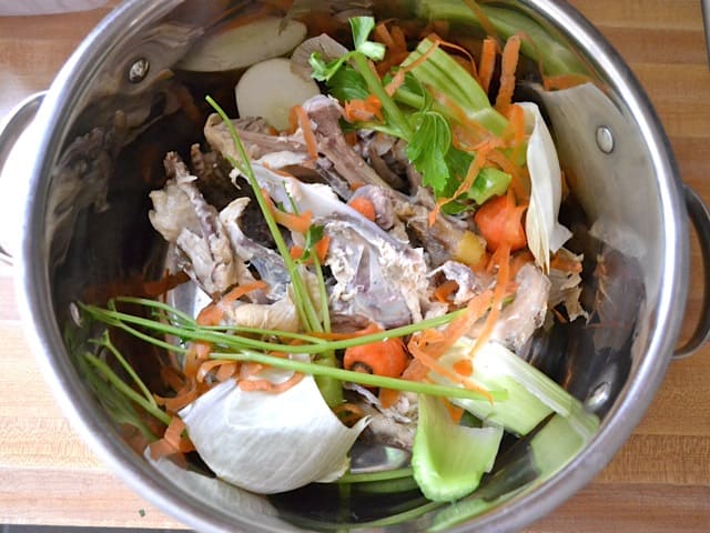veggies scraps and chicken pieces and check bones in pot 