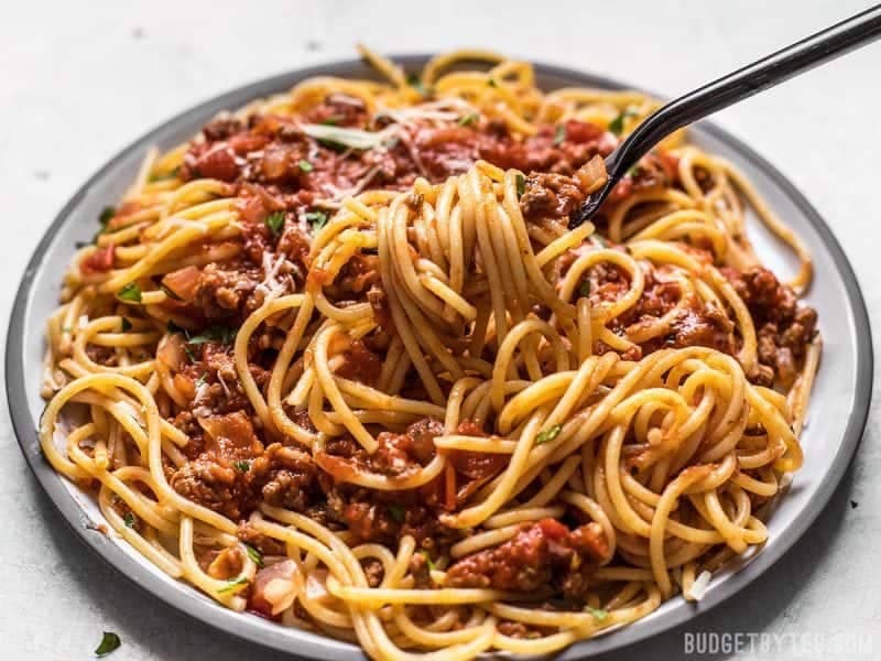A fork lifting spaghetti with The Best Weeknight Pasta Sauce off the plate