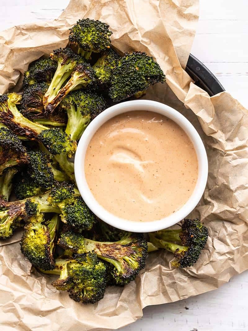 Overhead view of a bowl of comeback sauce surrounded by roasted broccoli