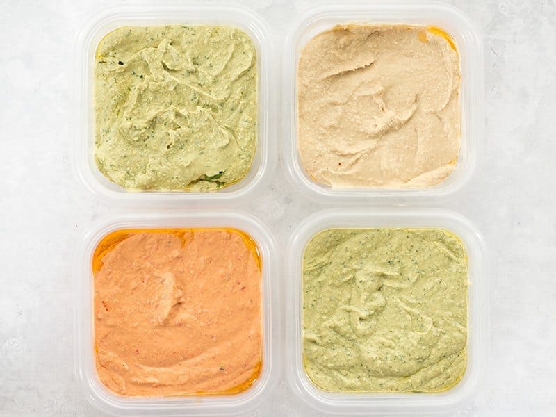Four flavors of homemade hummus in containers ready for the refrigerator