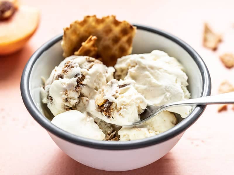 Front view of a bowl full of No Churn Balsamic Peach Ice Cream with a piece of waffle cone in the bowl.