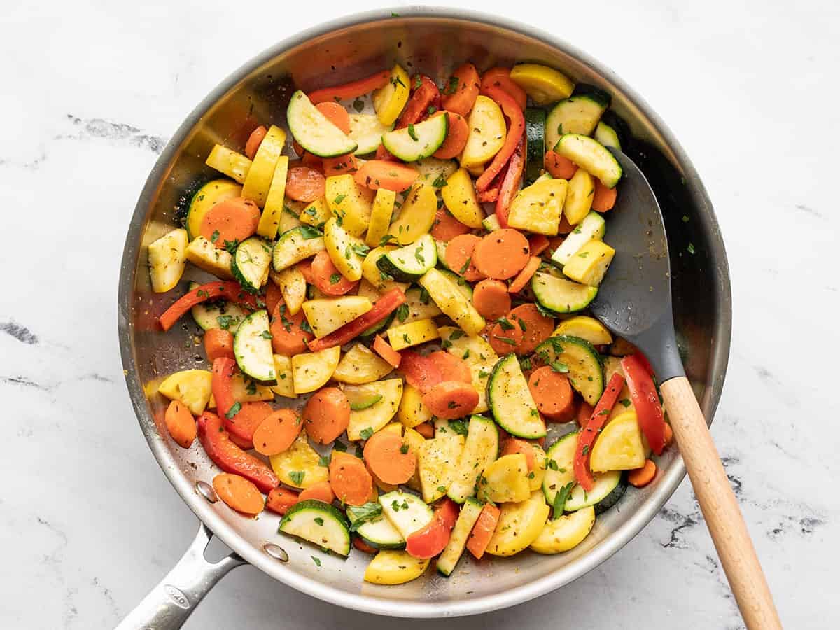 Finished sautéed vegetables in the skillet with a spatula
