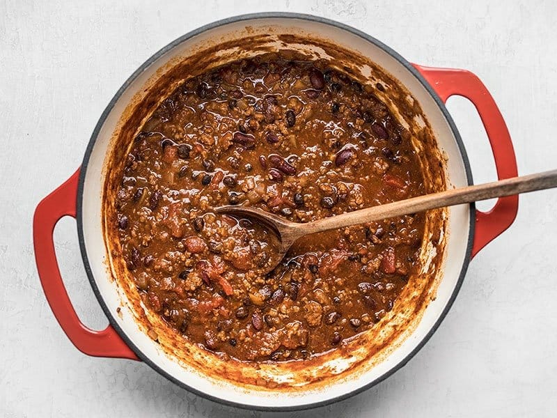Simmered homemade Chili with a wooden spoon