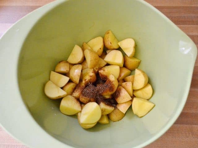 Chopped potatoes and seasoning added to mixing bowl 