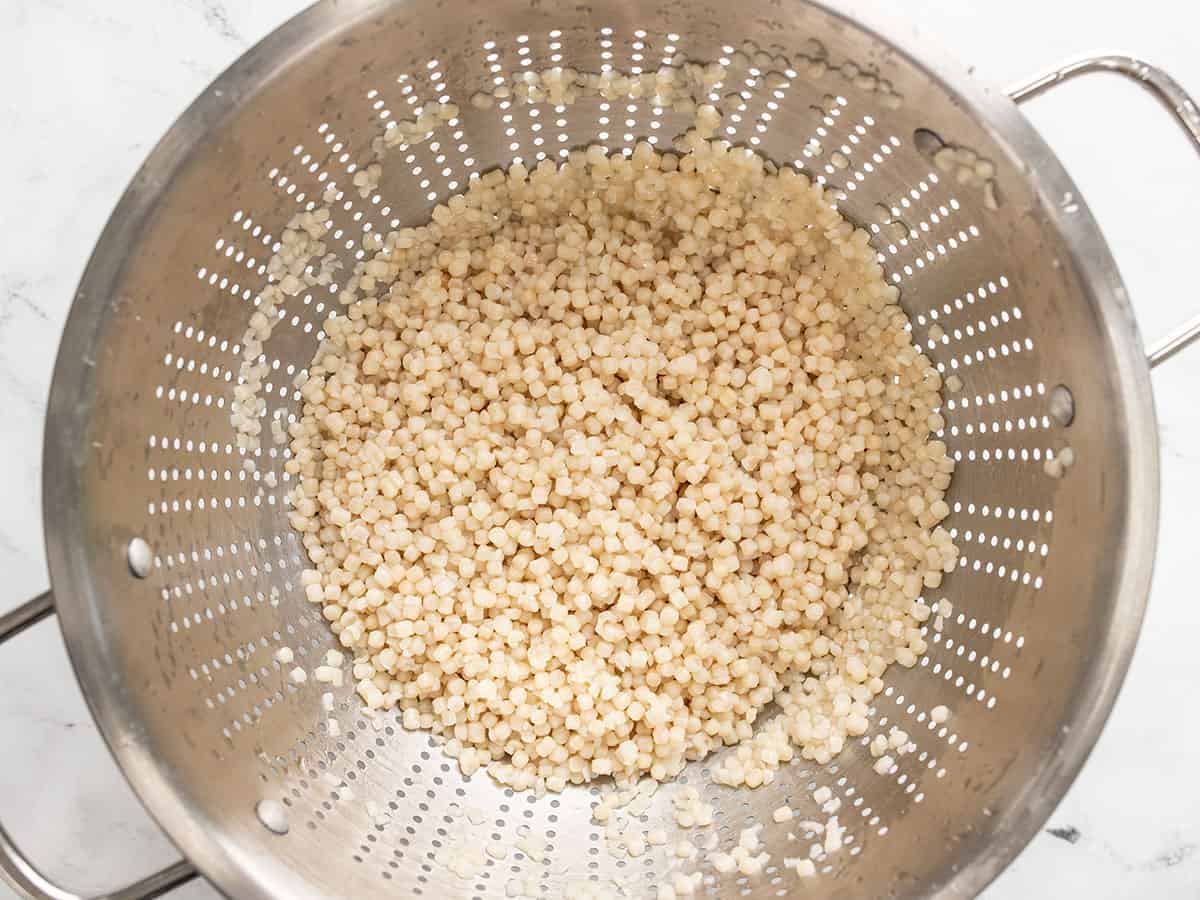 Cooked couscous draining in a colander.
