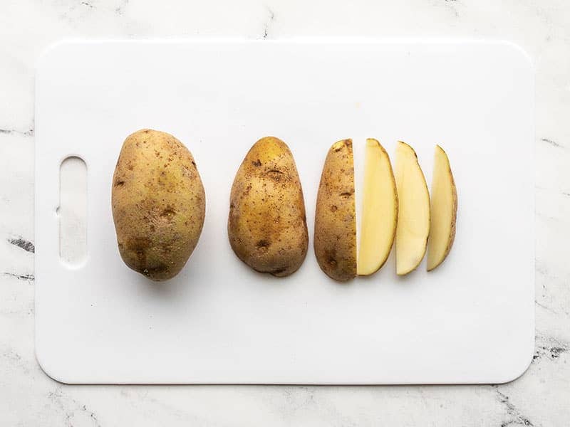 Potatoes cut into wedges on a cutting board