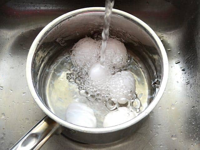 Adding water to eggs in pot 
