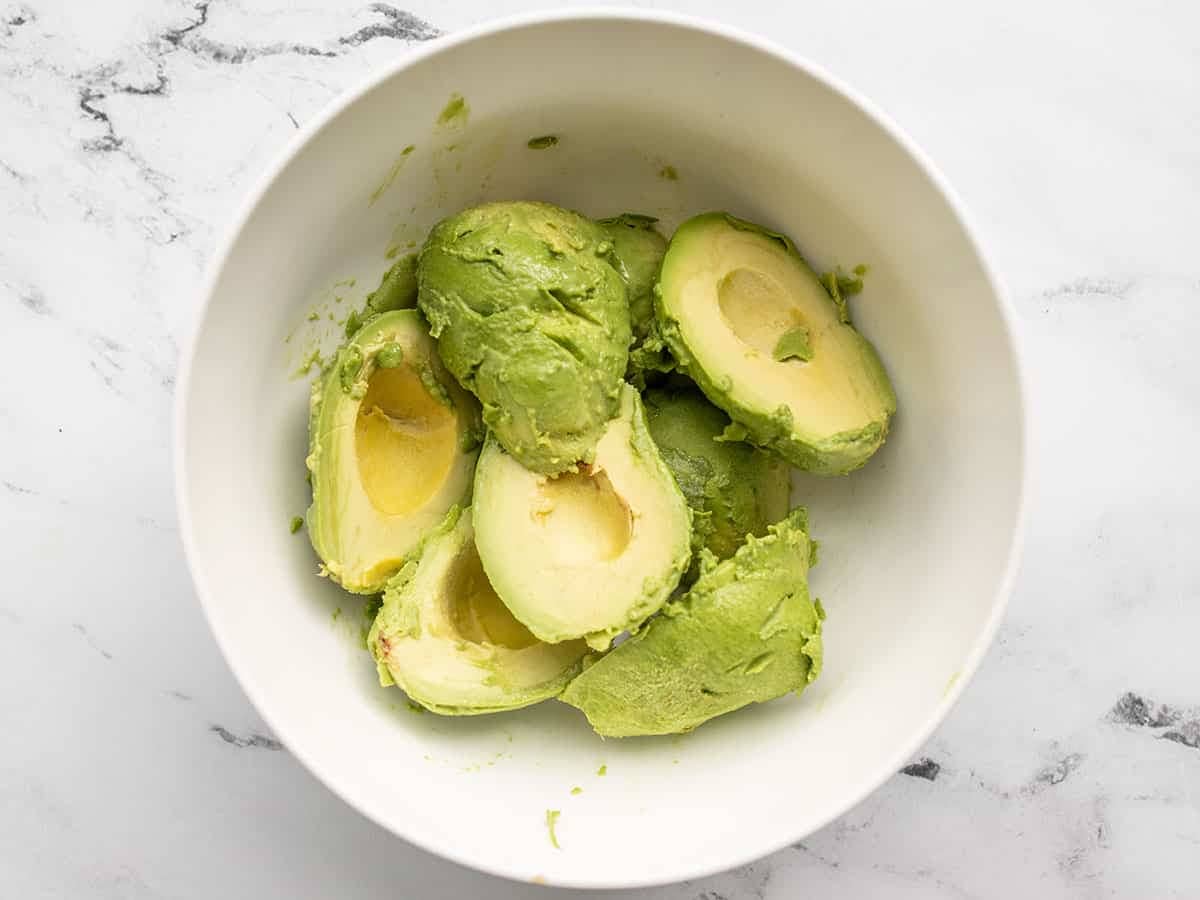 Peeled and seeded avocados in a bowl.