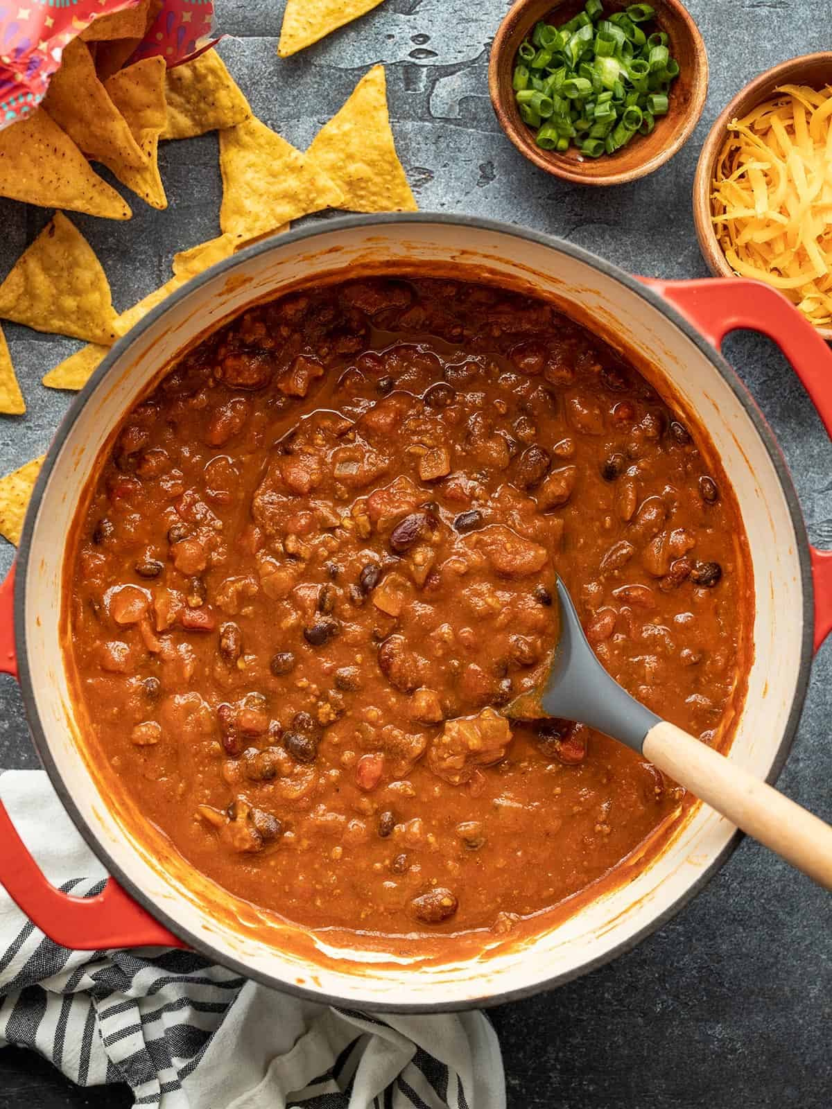 Overhead view of a pot of pumpkin chili with toppings on the sides