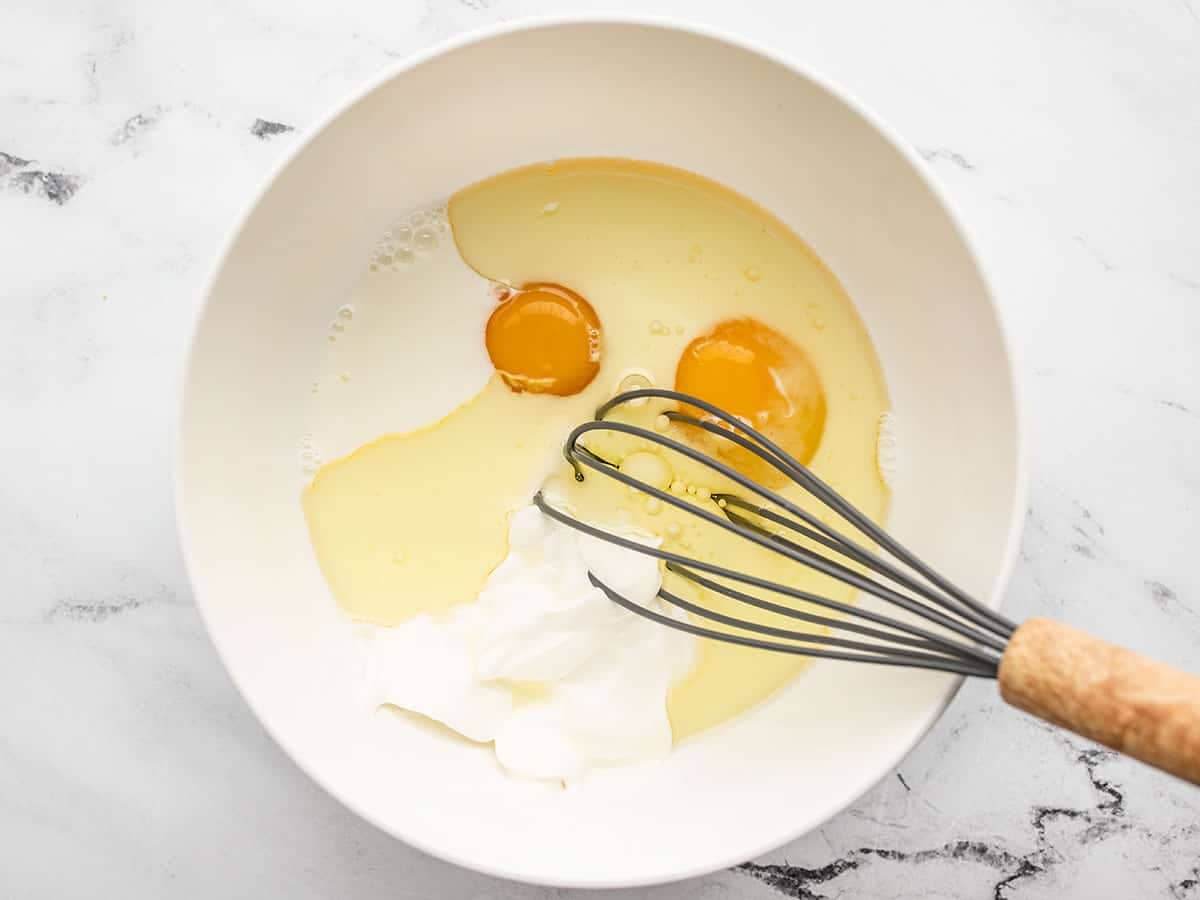 Eggs oil and milk in a bowl with a whisk