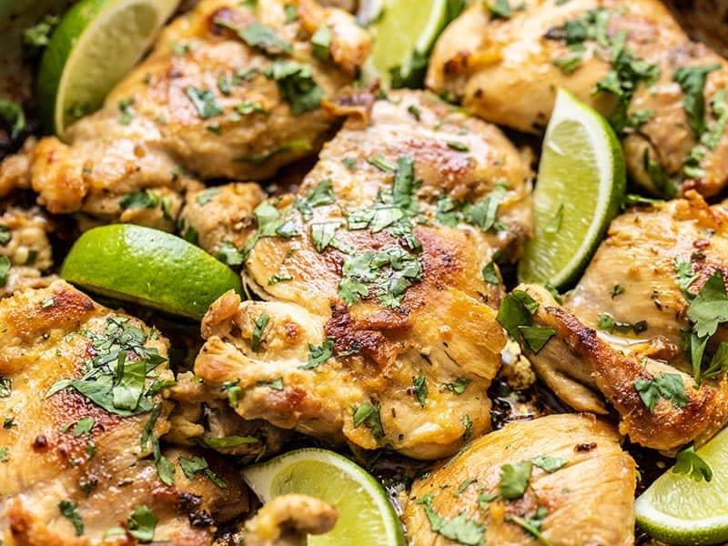 Close up of cooked Cilantro Lime Chicken garnished with fresh cilantro and lime wedges.