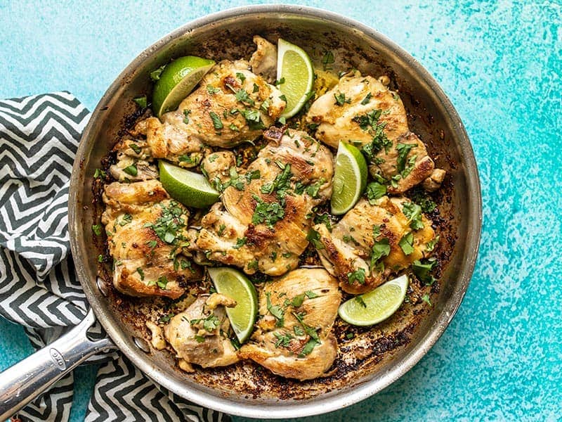 Finished Easy Cilantro Lime Chicken in the skillet with lime wedges