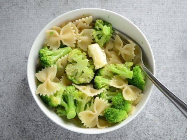 Butter added to hot pasta and broccoli in the bowl
