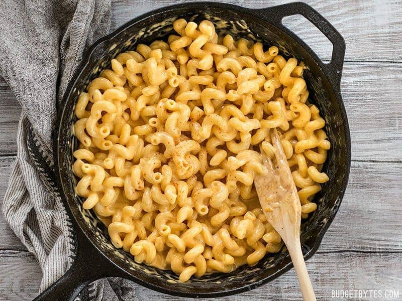 Overhead shot of a cast iron skillet full of mac and cheese with a wooden pasta fork