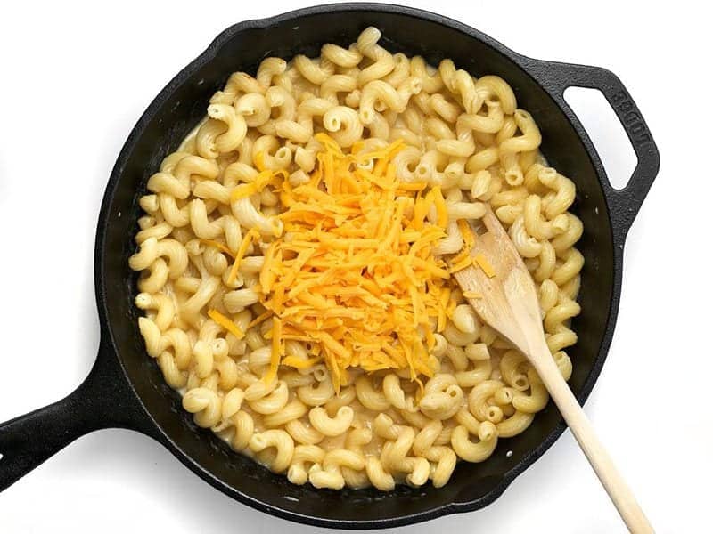 Shredded Cheese added to cast iron skillet with pasta