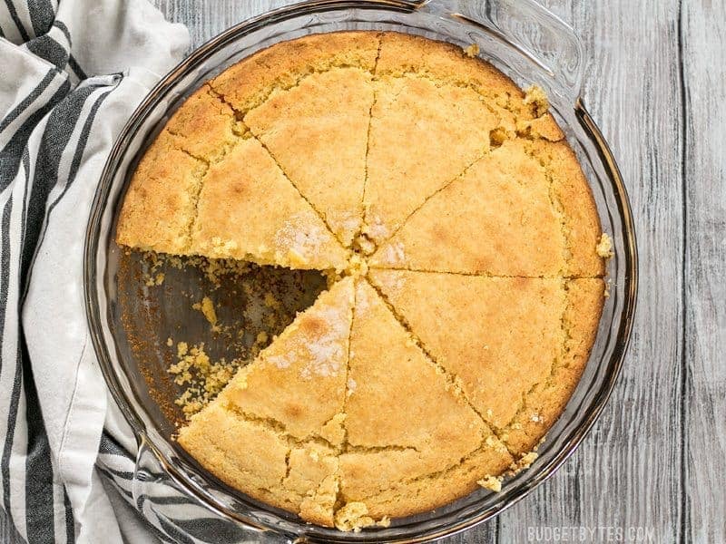 Homemade cornbread baked in a pie plate with one slice missing.