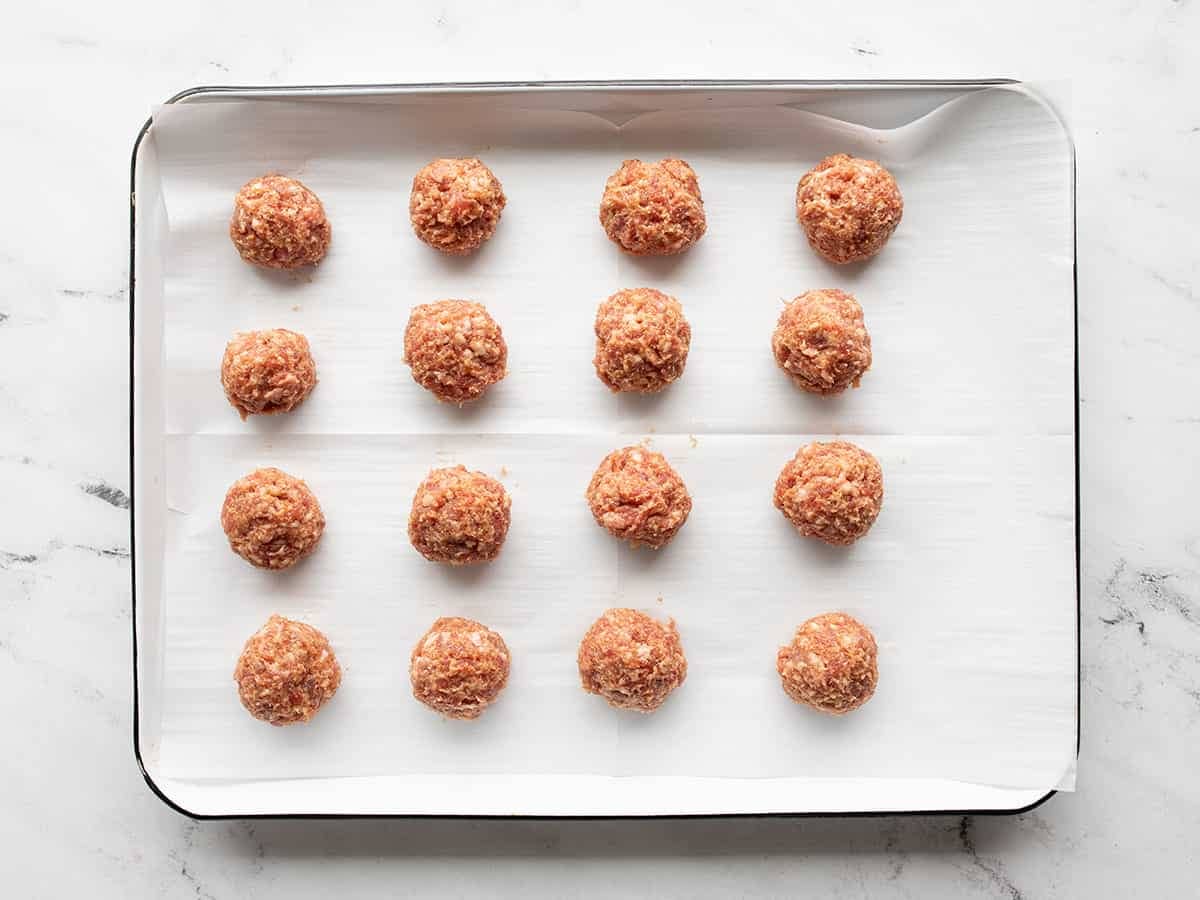 raw, shaped meatballs on the baking sheet