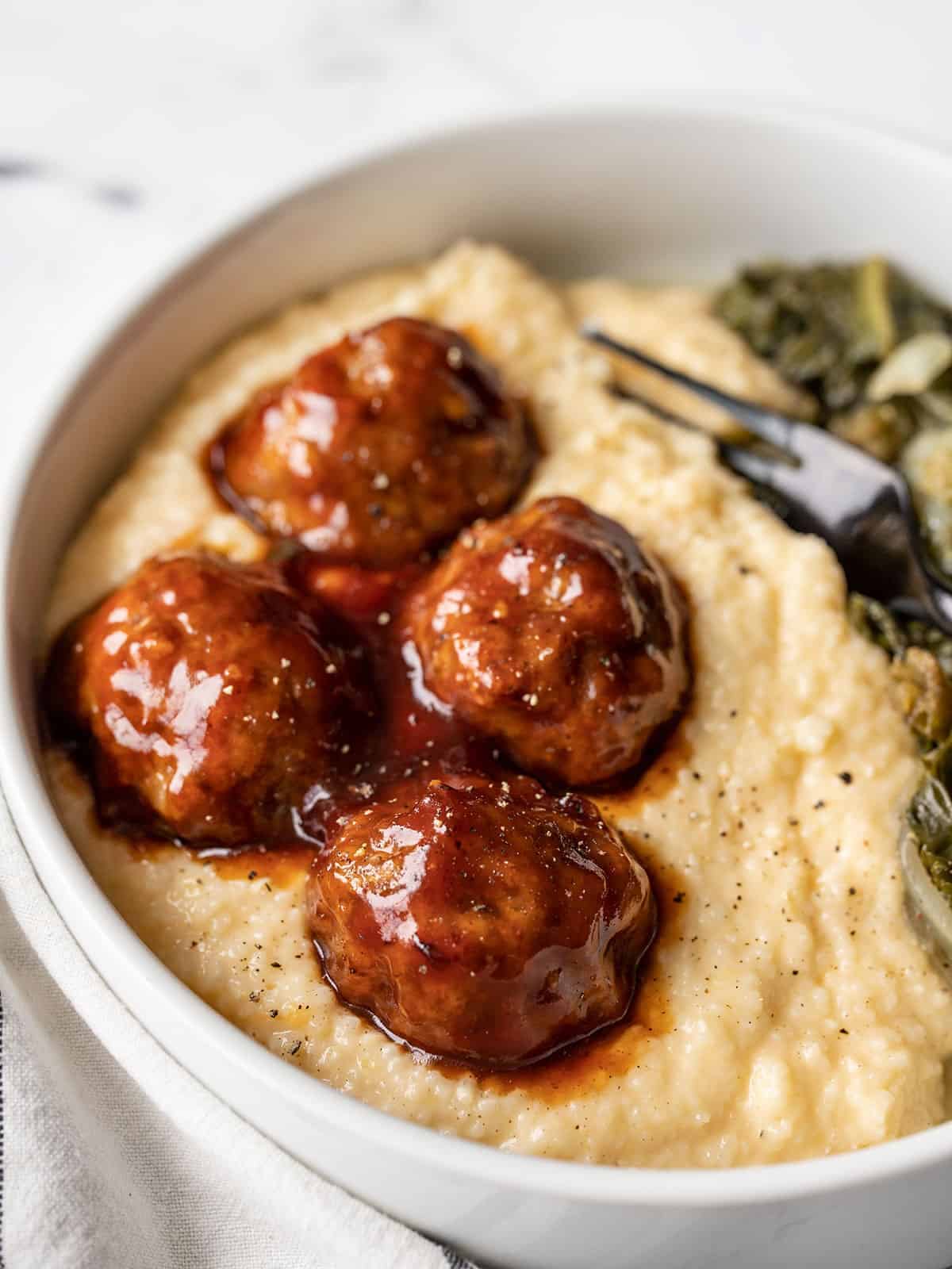 close up side view of bbq meatballs on cheese grits