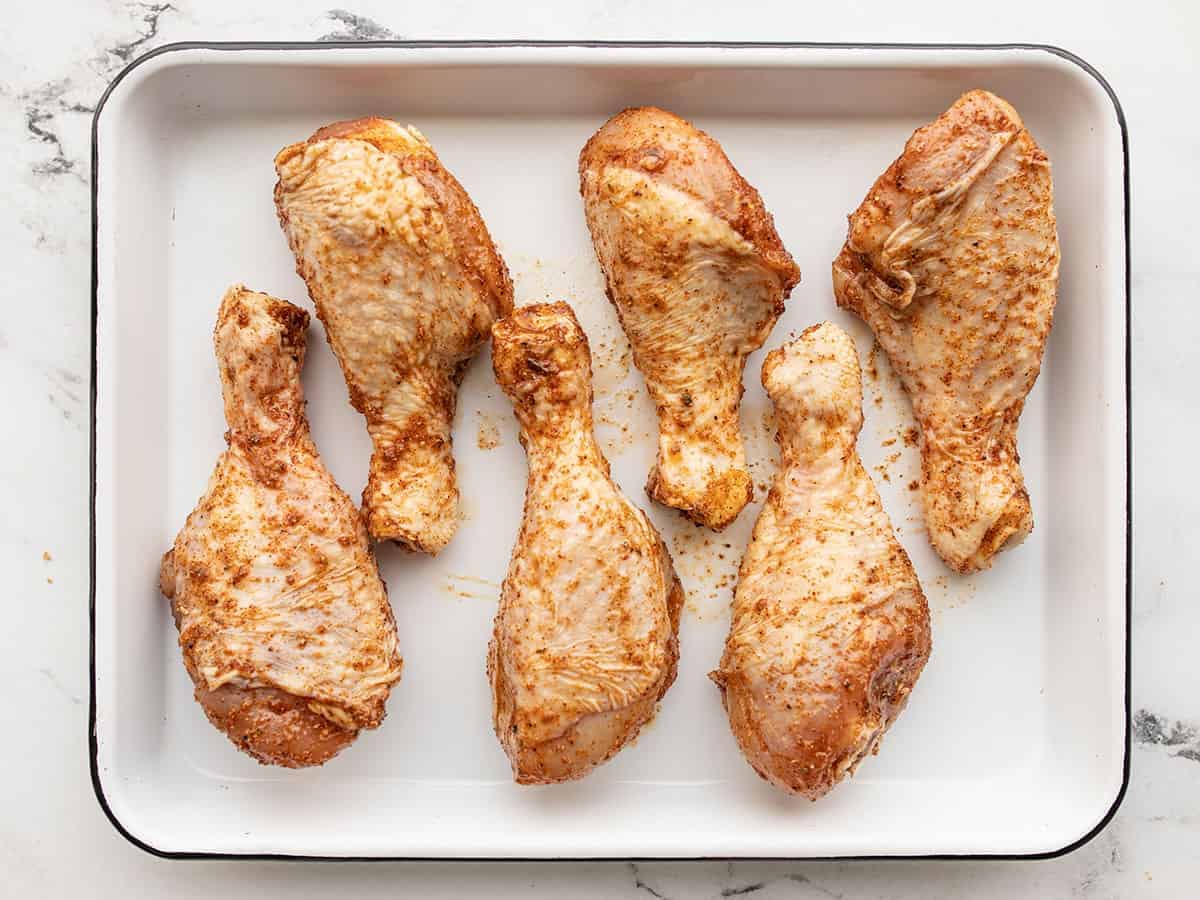 Raw seasoned chicken on a baking sheet