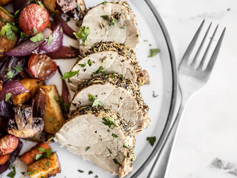 Herb Roasted Pork Tenderloin Slices on a plate with balsamic roasted vegetables