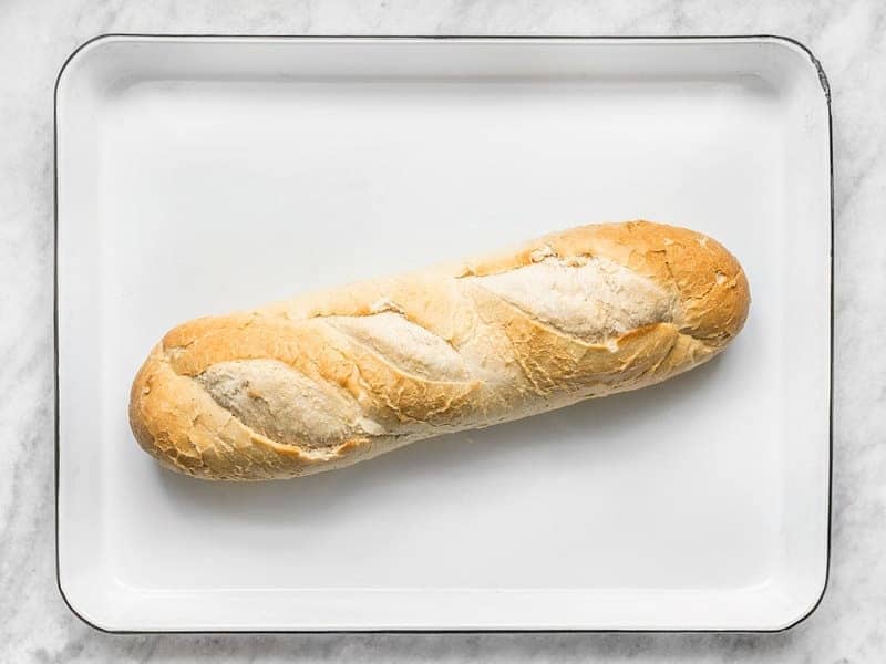 A loaf of French Bread on a white baking sheet
