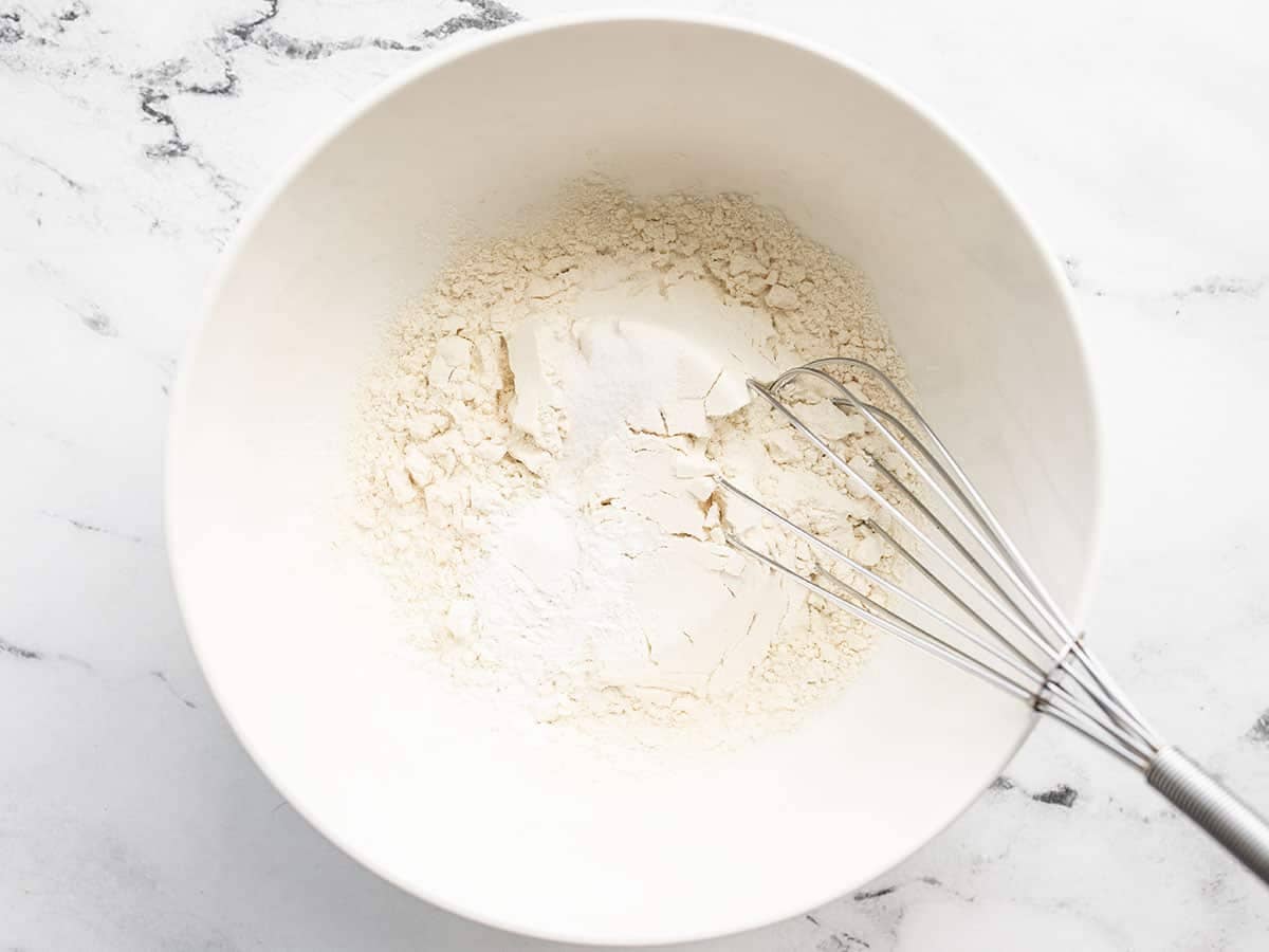 dry ingredients for pancakes in a bowl with a whisk.