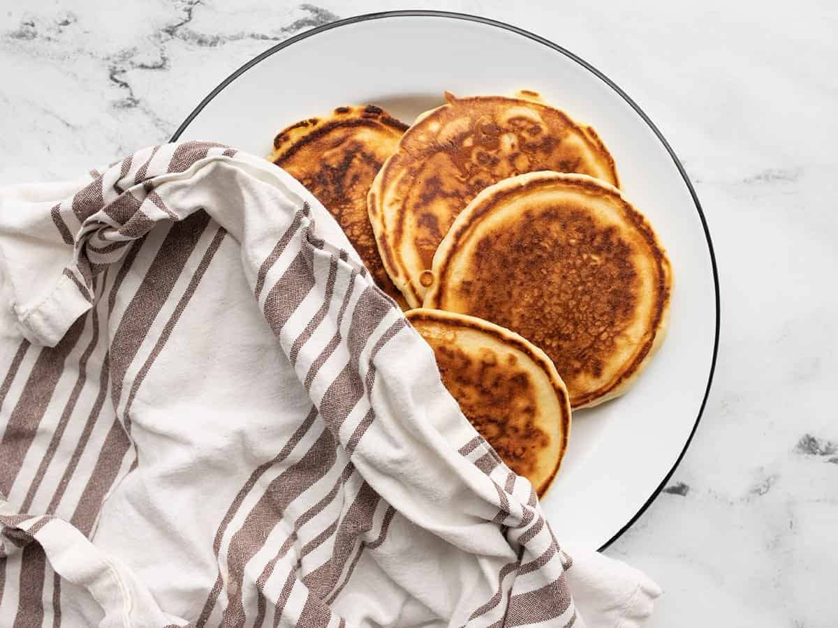 Pancakes on a plate covered with a towel.