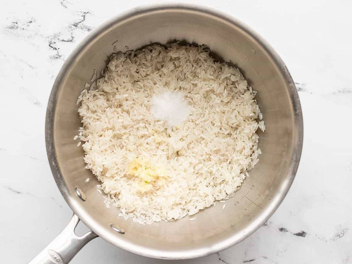 Rinsed rice in a saucepot with minced garlic and salt.