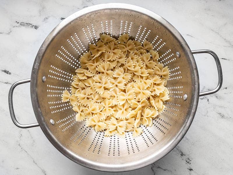 Cooked bowtie pasta draining in a colander. 