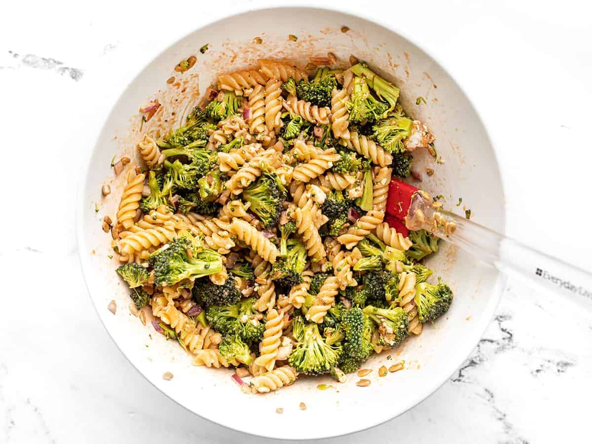 Finished broccoli pasta salad in a bowl with a red spatula