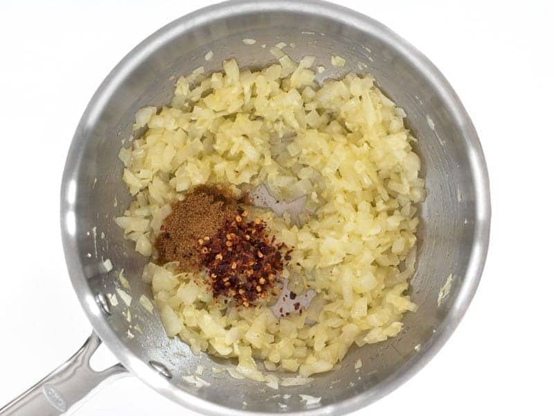 Cumin and Red Pepper flakes added to onion mixture in pot 