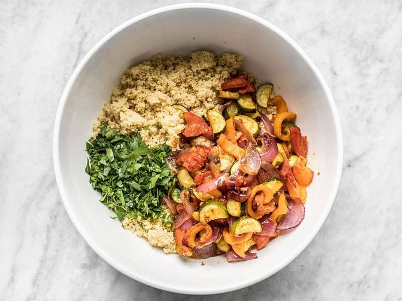 Couscous, roasted vegetables, and chopped parsley in a bowl