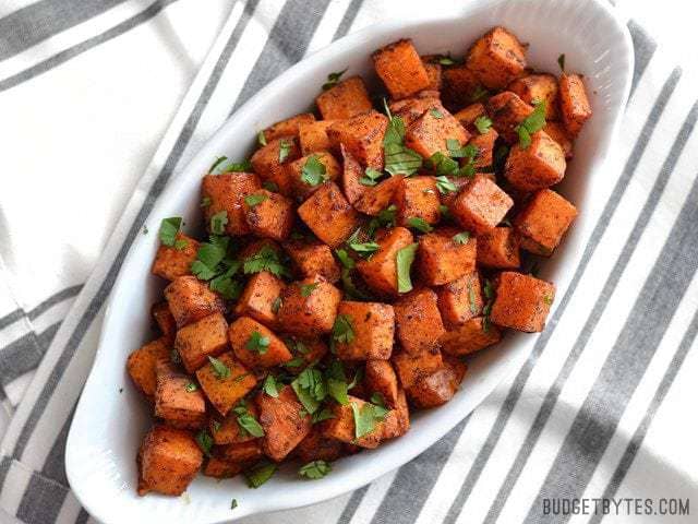 A serving dish full of Chili Roasted Sweet Potatoes garnished with cilantro