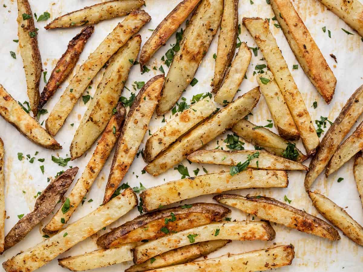 baked garlic parmesan fries on a baking sheet garnished with parsley