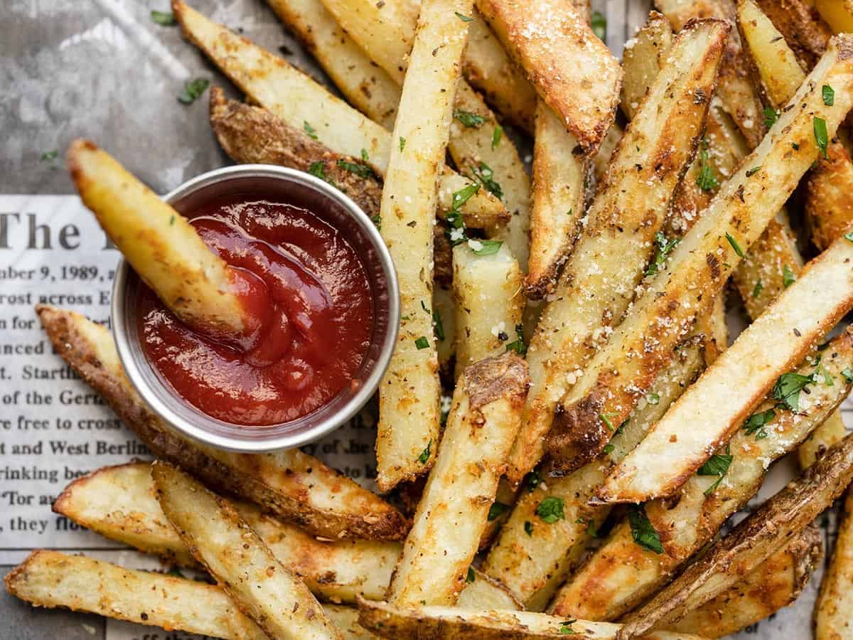 close up view of garlic parmesan fries and a cup of ketcheup
