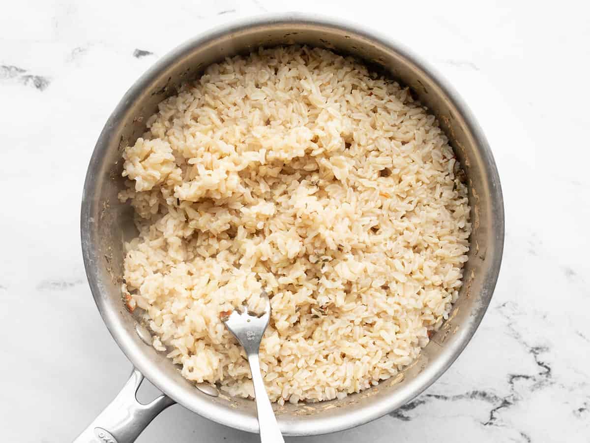 Brown rice being fluffed in the pot with a fork