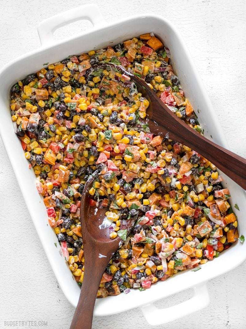 Roasted Sweet Potato Rainbow Salad in a large serving dish with two wooden serving spoons