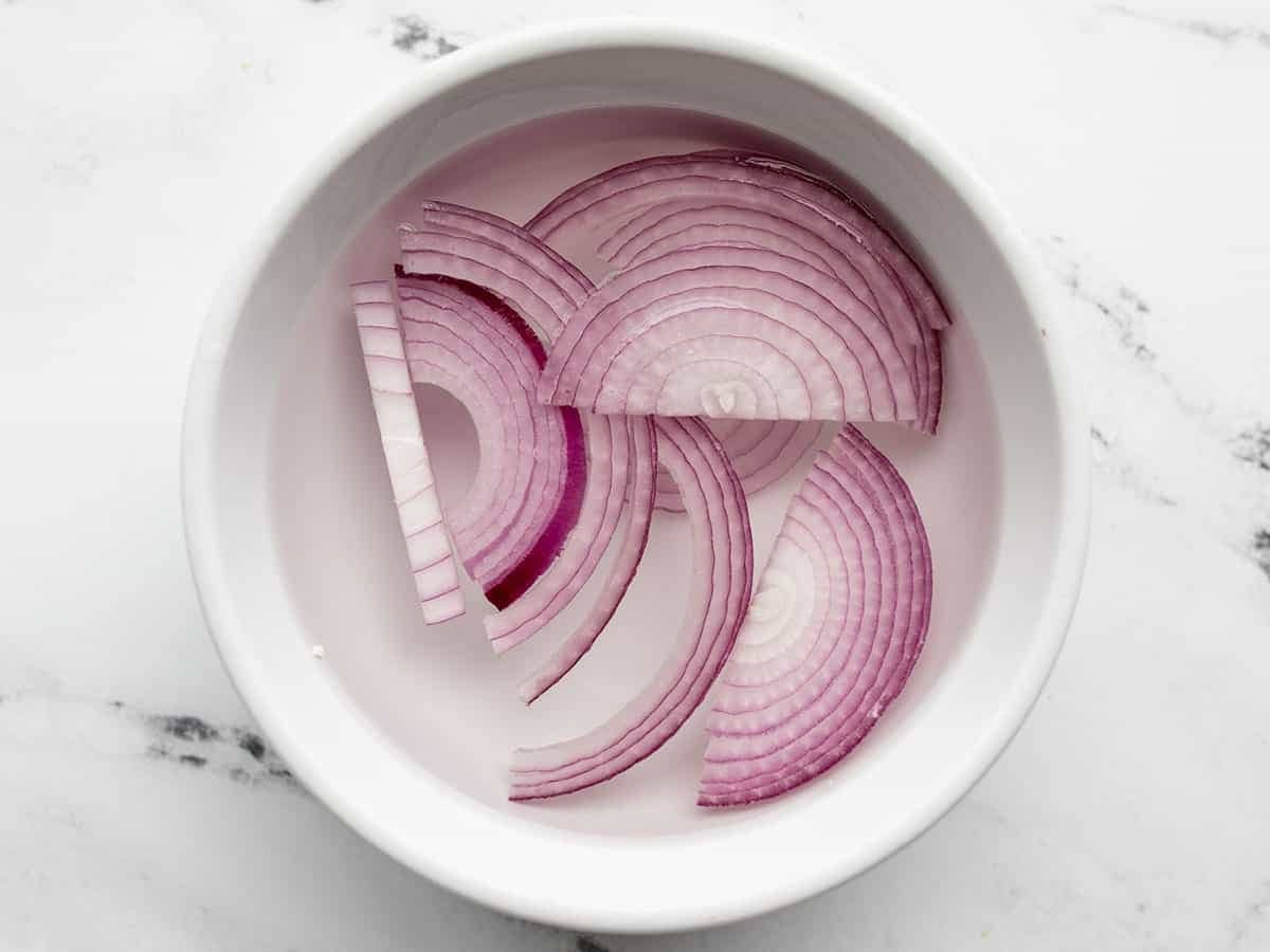 red onion slices soaking in a bowl of water