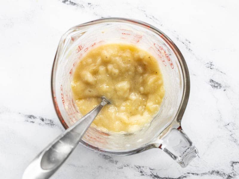 Mashed banana in a measuring cup with a fork