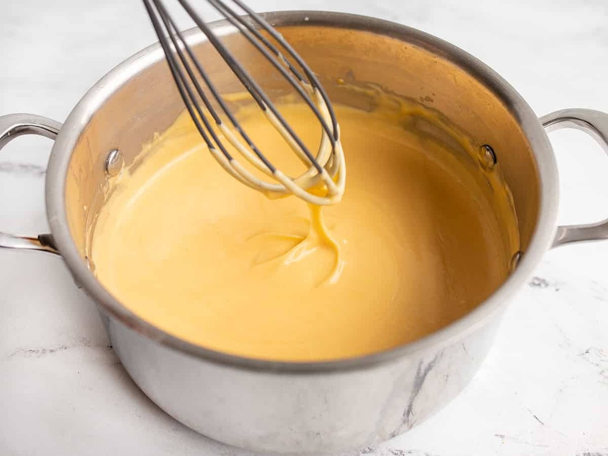 Finished cheese sauce dripping off the whisk