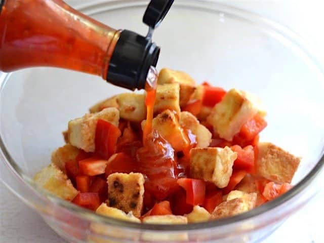 Sweet Chili Sauce being poured on the tofu and red bell pepper